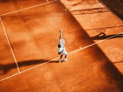 Tennisser op een gravelbaan, van bovenaf