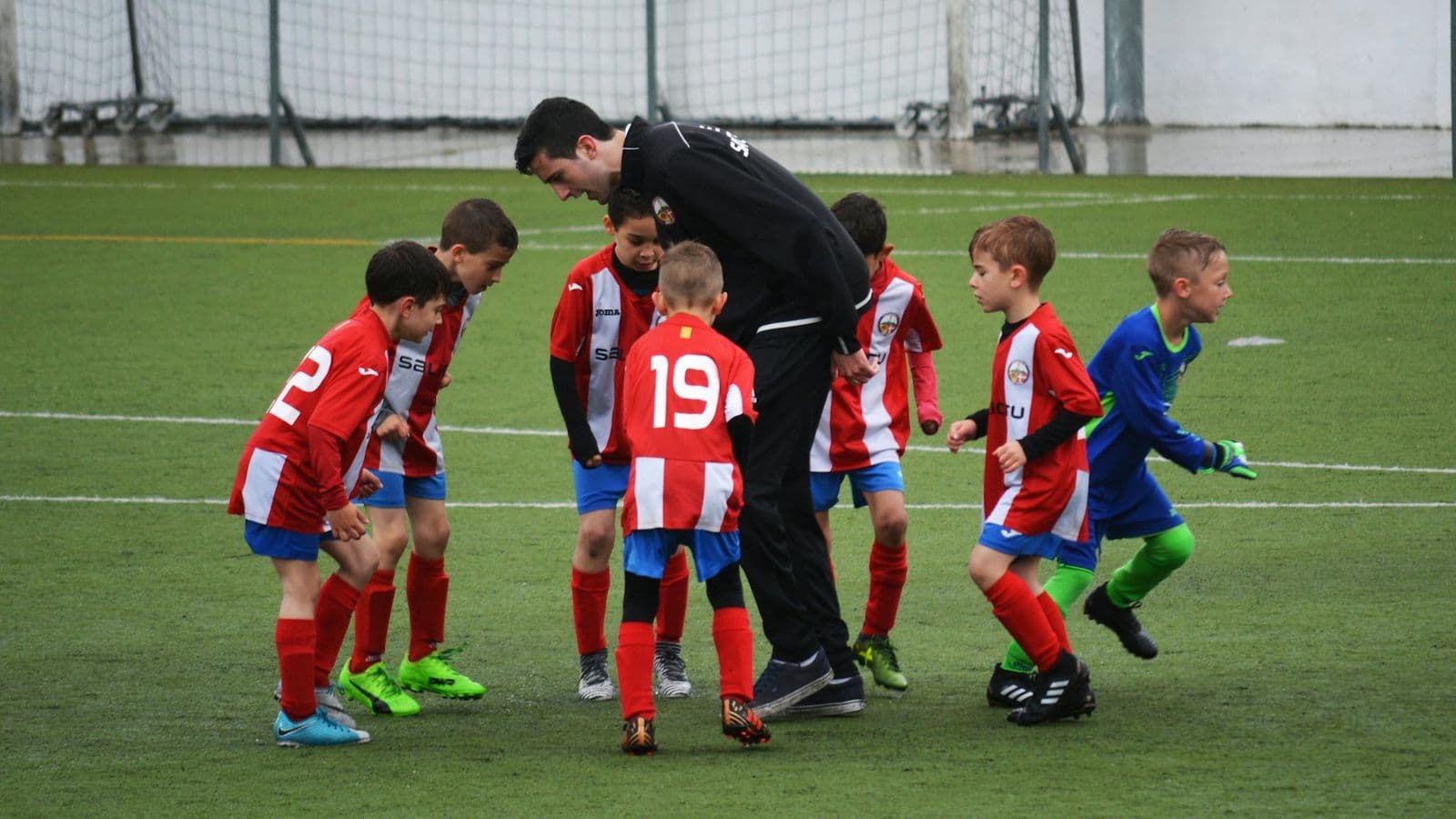 Trainer met jeugdspelers op het veld