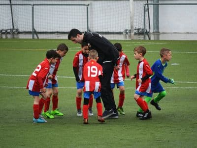 Trainer met jeugdspelers op het veld