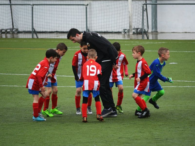 Trainer met jeugdspelers op het veld